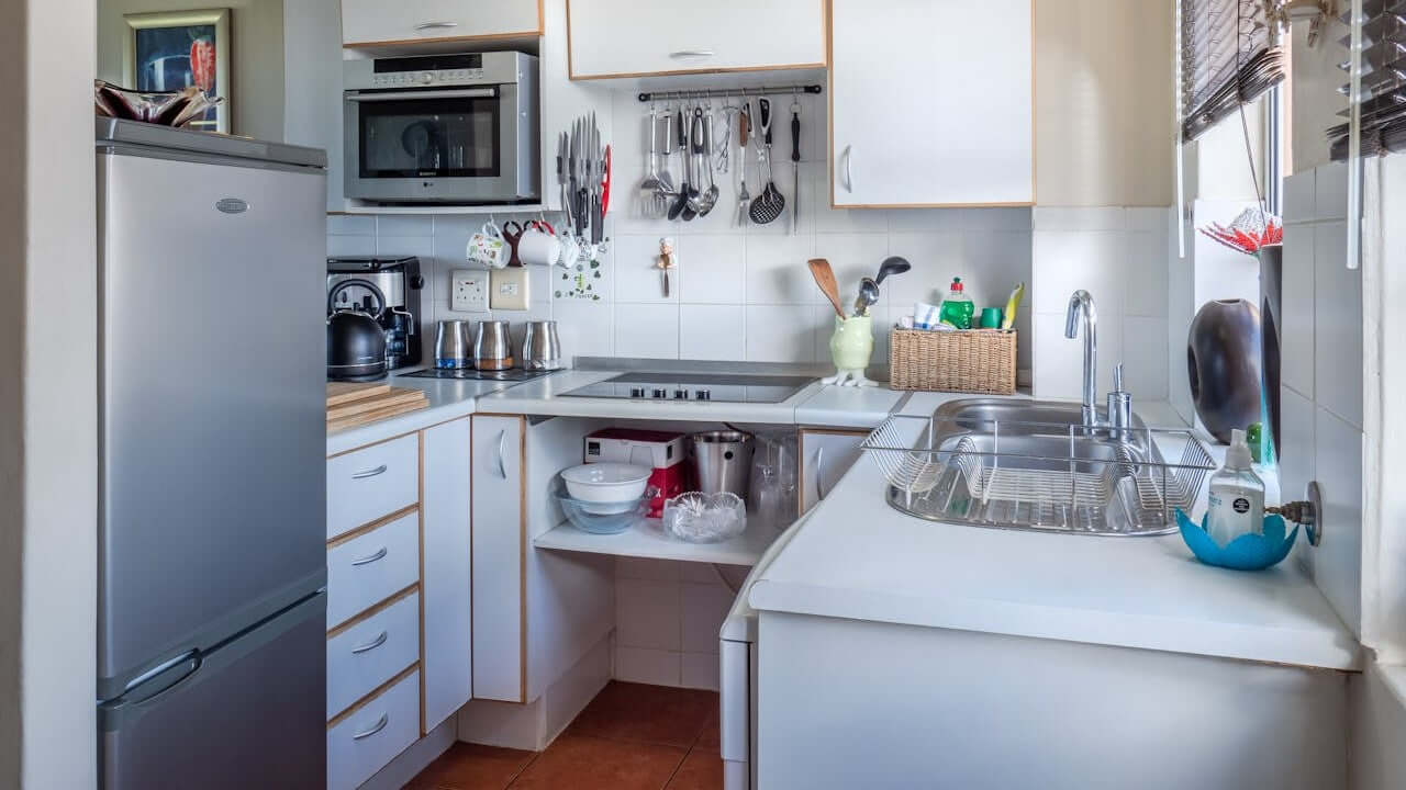 Small kitchen with compact appliances, wall-mounted utensils, and organized countertop for efficient small kitchen solutions.