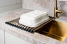 Stainless steel roll-up dish drying rack with silicone ends, designed for space-saving kitchen use.