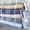 Stack of folded Cotton Turkish towels in various colors on a wooden surface