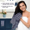 Woman holding a striped towel with text about organic cotton towels in a bathroom setting
