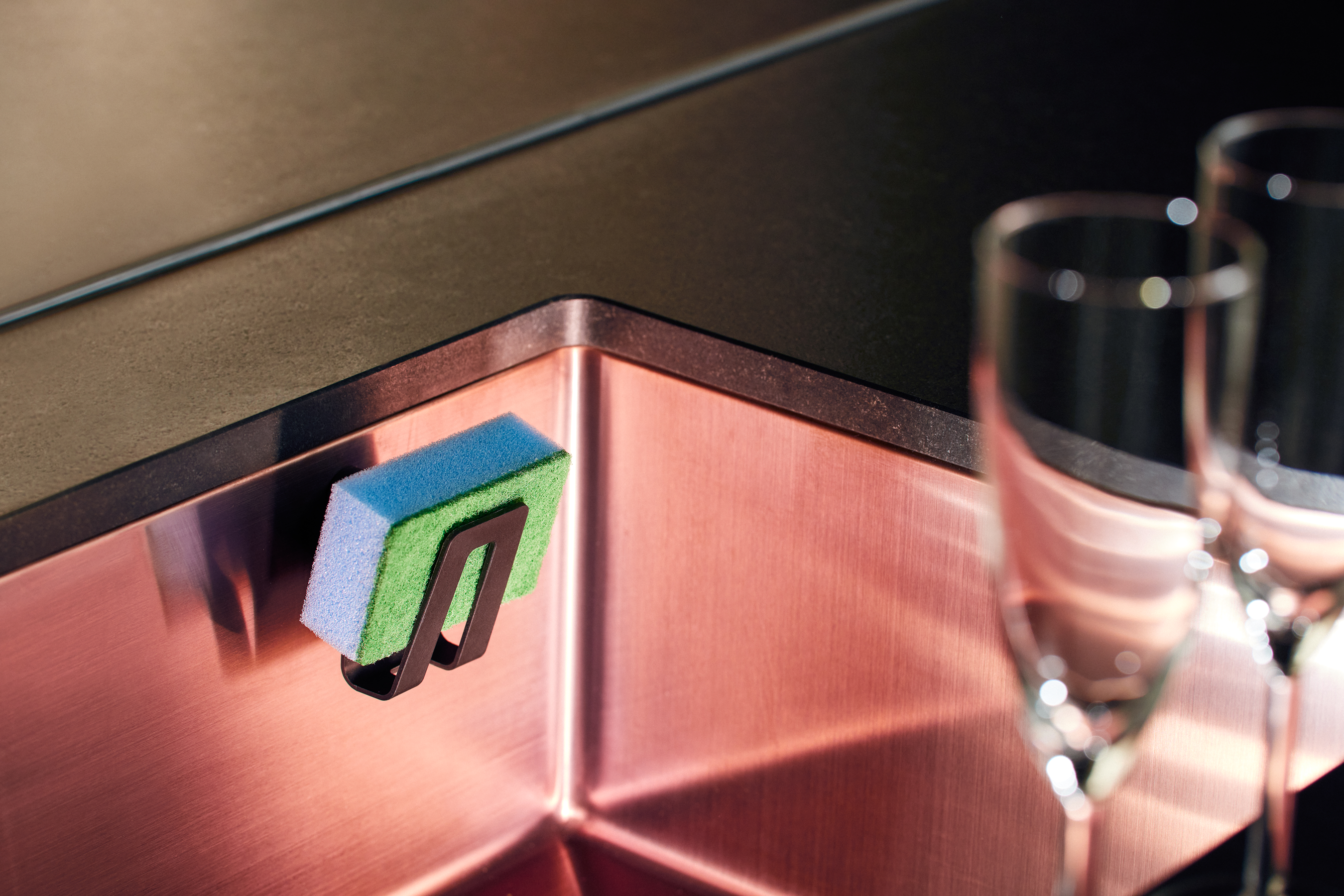 Biocomposite sponge holder with magnetic attachment in a kitchen sink.